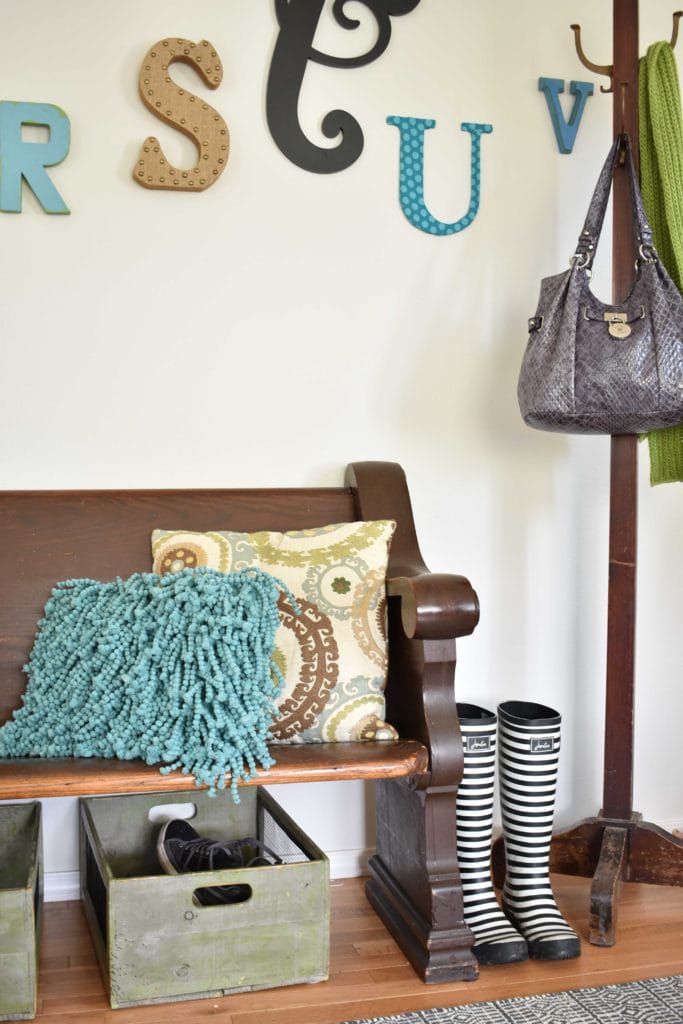 entryway with a church pew and bins for shoes underneath it