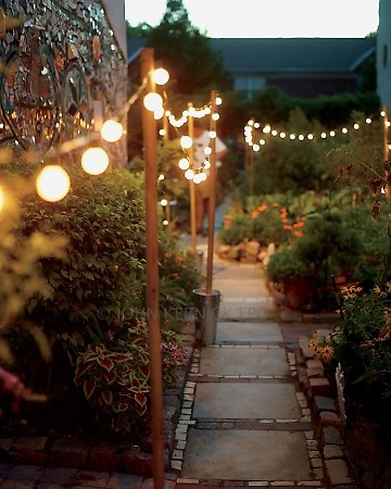 backyard path lit by string lights suspended from poles