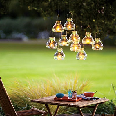 a group of mini candle lanterns suspended from a tree branch