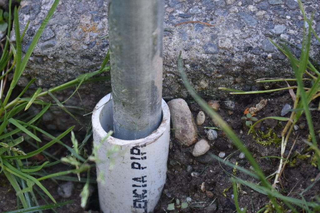 close-up of PVC pipe in the ground supporting an electrical conduit string light pole