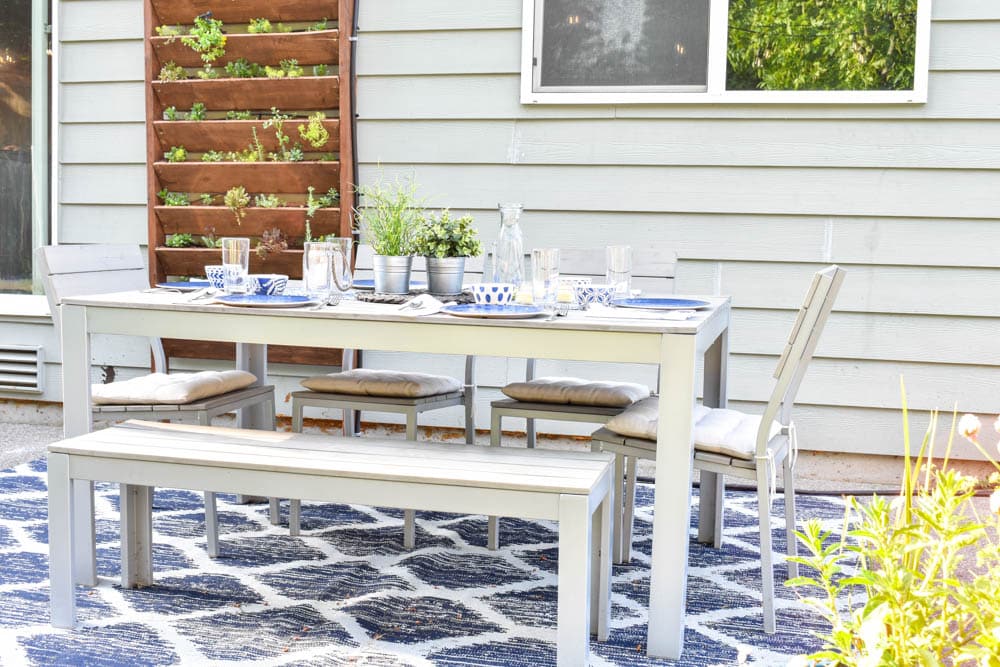 This simple and budget-friendly dining patio makeover transforms a small ugly concrete slab patio into a beautiful outdoor dining room. There's a vertical garden, string lights, an outdoor rug, and more!