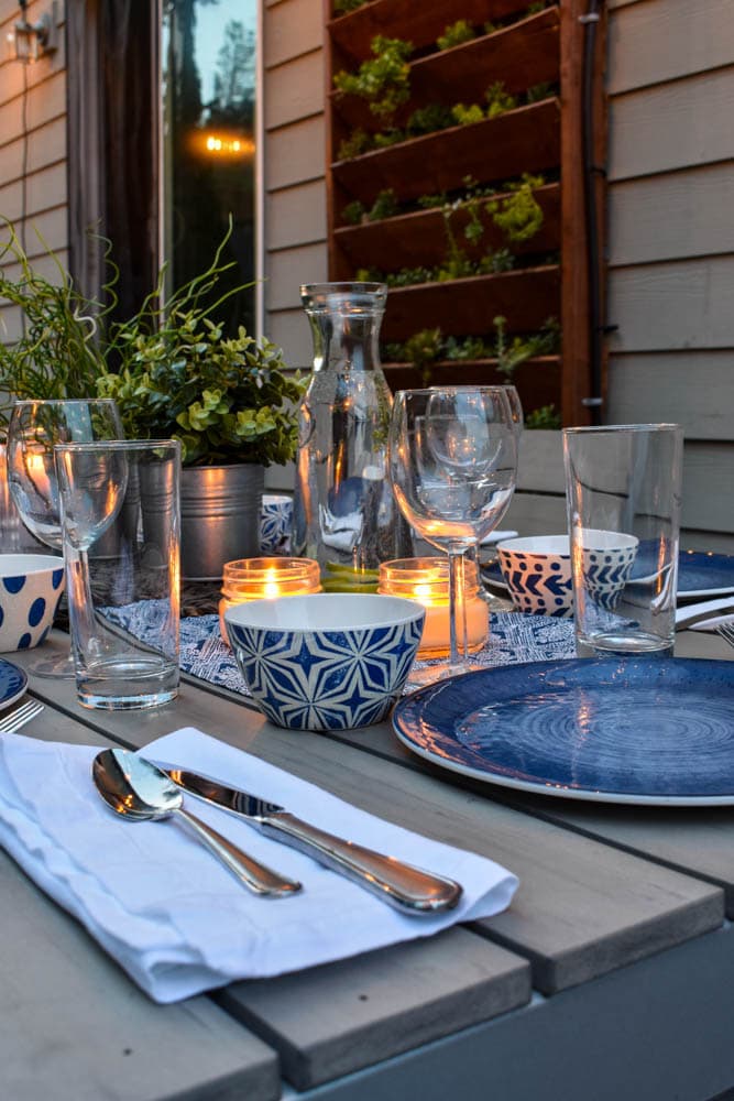 This simple and budget-friendly dining patio makeover transforms a small ugly concrete slab patio into a beautiful outdoor dining room. There's a vertical garden, string lights, an outdoor rug, and more!