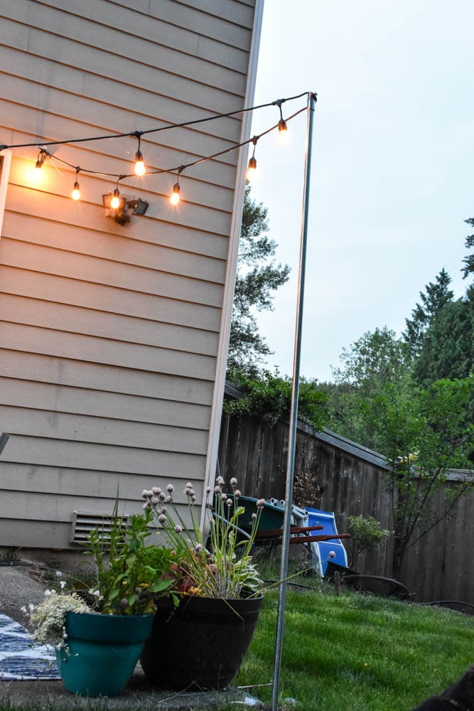 This simple and budget-friendly dining patio makeover transforms a small ugly concrete slab patio into a beautiful outdoor dining room. There's a vertical garden, string lights, an outdoor rug, and more!