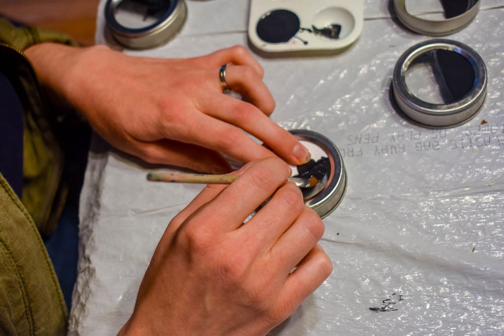 photo of someone painting a magnetic spice jar lid with chalkboard paint