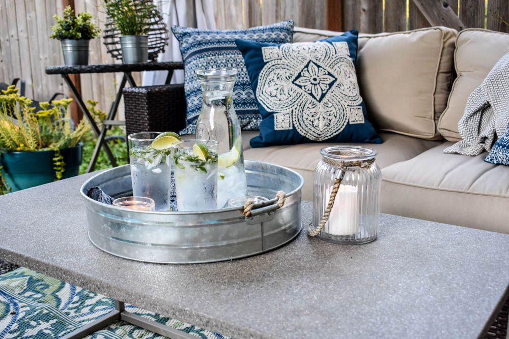 This covered outdoor living room on a budget is the perfect backyard Summer spot to relax! It's got a fireplace to roast marshmallows, cozy modern furniture, and an outdoor rug.