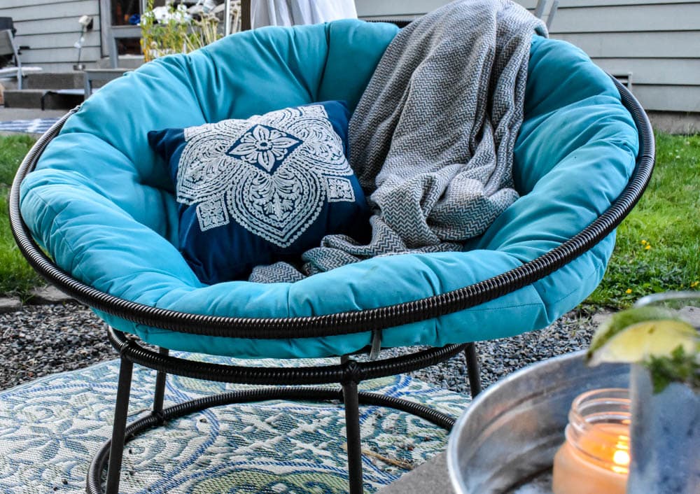 outdoor papasan chair with a pillow and blanket