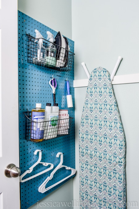 This small laundry room makeover on a budget makes the most of every square inch! It includes a stackable washer and dryer, sorting space, laundry basket storage, an ironing board, and space for detergent and cleaning supplies!