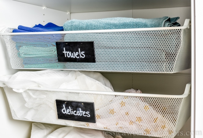 This small laundry room makeover on a budget makes the most of every square inch! It includes a stackable washer and dryer, sorting space, laundry basket storage, an ironing board, and space for detergent and cleaning supplies!