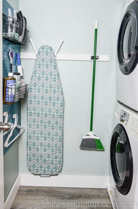 This small laundry room makeover on a budget makes the most of every square inch! It includes a stackable washer and dryer, sorting space, laundry basket storage, an ironing board, and space for detergent and cleaning supplies!