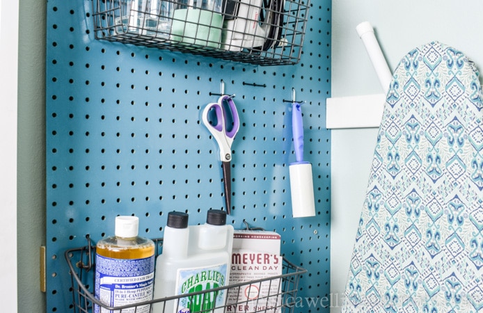 This small laundry room makeover on a budget makes the most of every square inch! It includes a stackable washer and dryer, sorting space, laundry basket storage, an ironing board, and space for detergent and cleaning supplies!