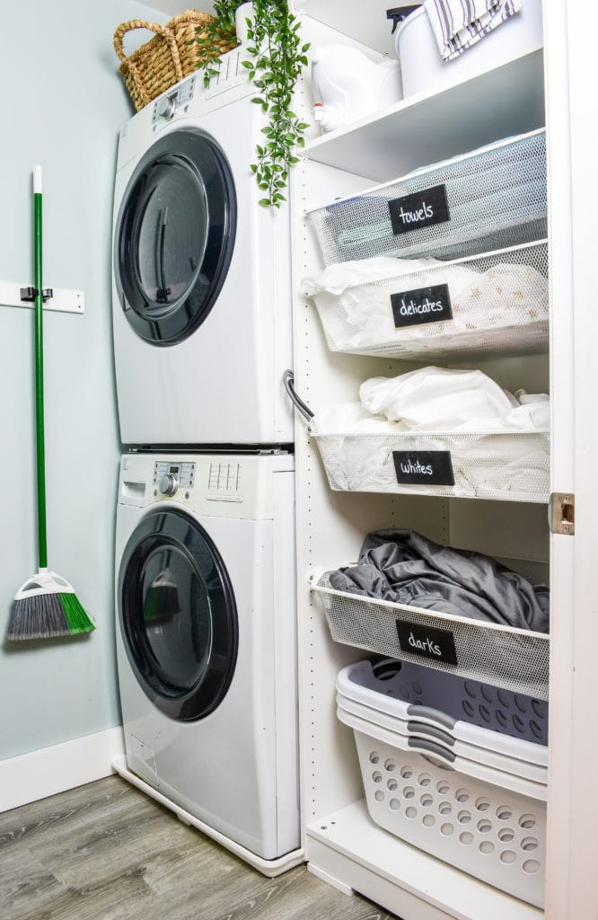small laundry room with a stacked washer and dryer and open cabinet for laundry baskets