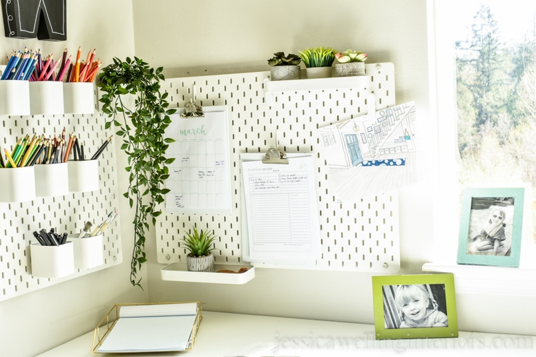 ikea home office with Skadis pegboards in corner with rainbow colored pencils, clipboards, and indoor plants