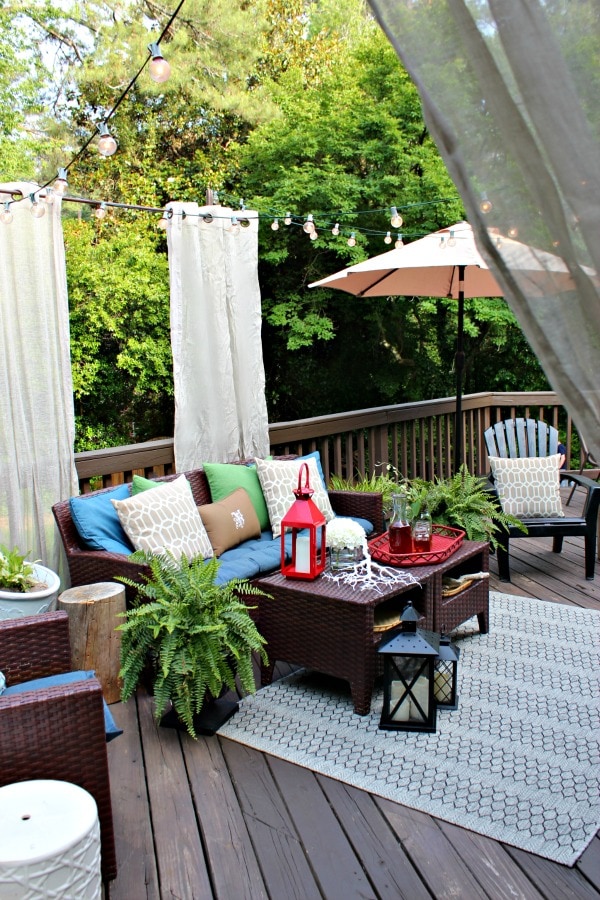 colorful deck seating area with outdoor curtains and string lights as a patio shade idea