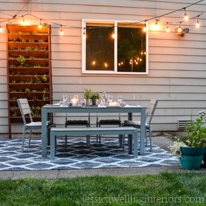 patio trasero con juego de comedor, jardín vertical y luces de cuerda