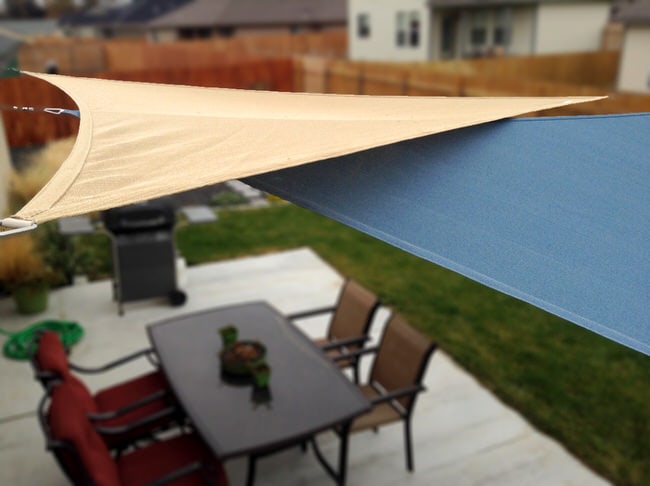 two overlapping shade sails over a patio dining space