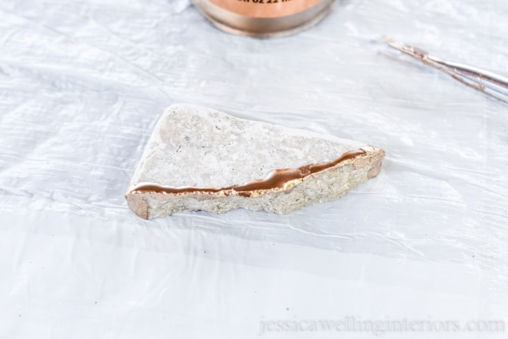 image of someone painting gold leaf paint on broken tile to make kintsugi coasters