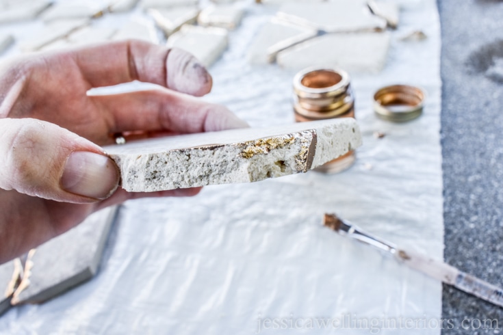 image of someone painting gold leaf paint on tile to make kintsugi coasters