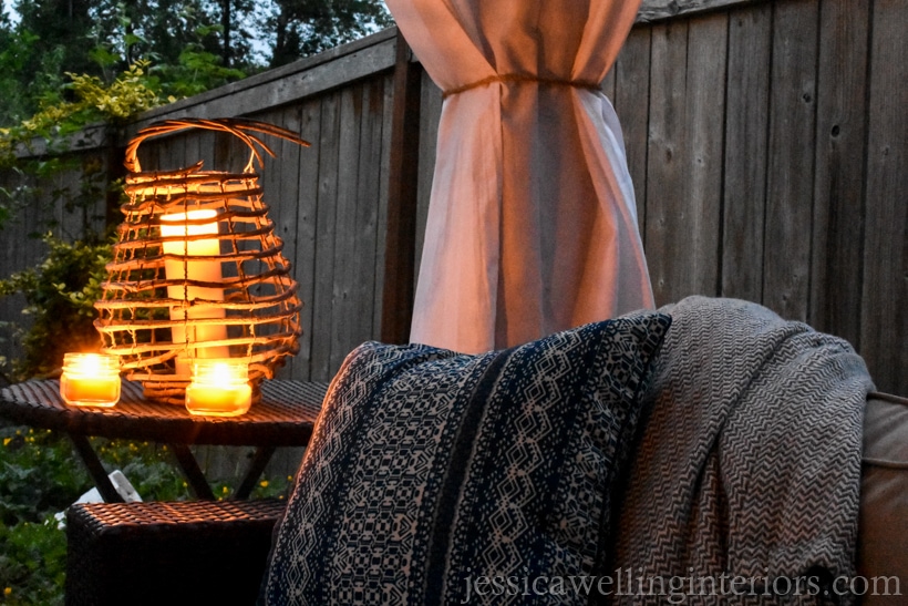 end of outdoor sofa and end table with glowing candle lanterns