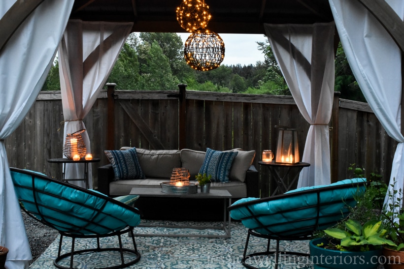 outdoor living space lit with an outdoor chandelier and glowing candle lanterns