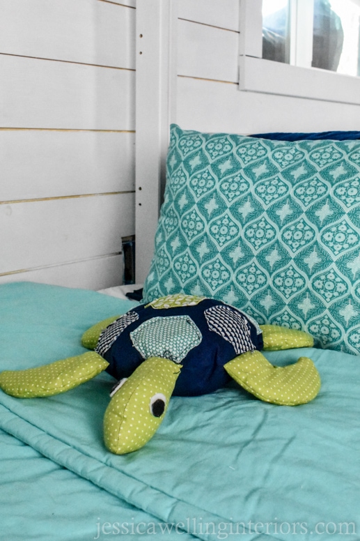 stuffed sea turtle on a child's bunk bed with aqua colored bedding