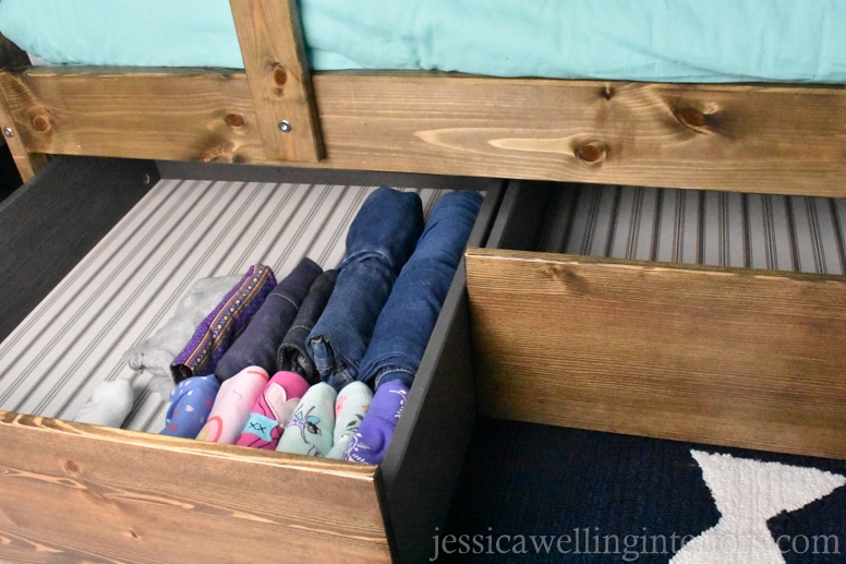 kids bunk room with IKEA hack under-bed storage drawer pulled out with child's clothing folded inside