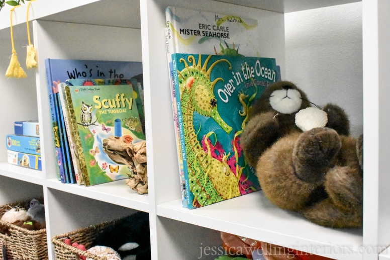 IKEA KALLAX bookshelf in white with ocean-themed children's books and a stuffed otter in a beach house bunk room