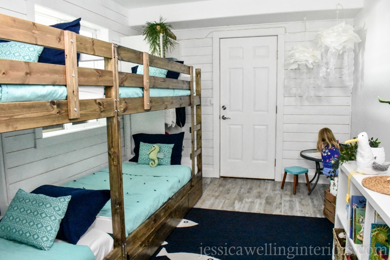 full view of beach house bunk room with IKEA MYDAL bunk beds, fish rug, and jellyfish lights