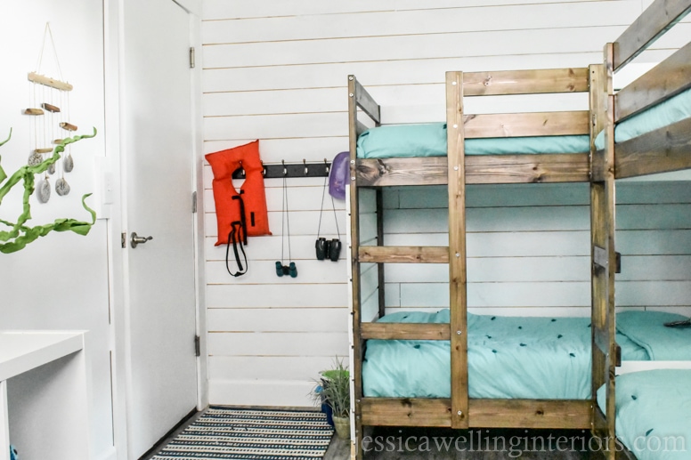 beach house bunk room with aqua bedding, and an entry way with storage hooks and a life jacket