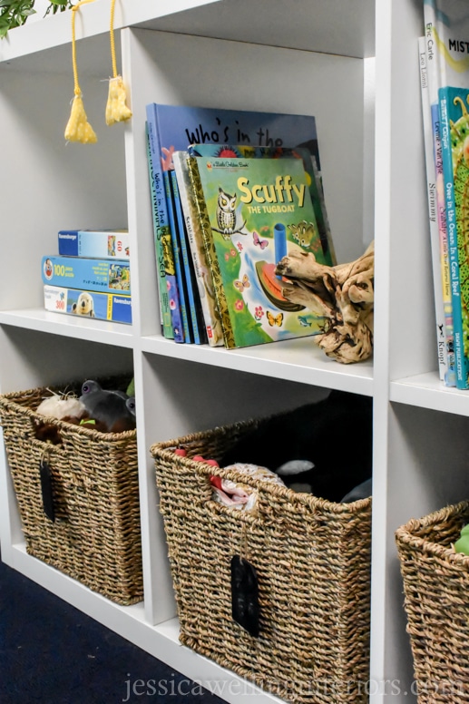 IKEA Kallax bookcase with a collection of ocean-themed children's books- Scuffy the Tugboat in front, and baskets of toy stuffed sea creatures.