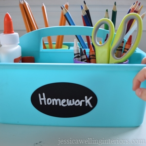 small blue supply caddy full of school supplies-scissors, pencils, glue, crayons, etc. with label "homework" on the front