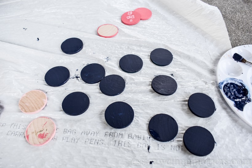 wood coins being painted with acrylic paint and laid out to dry