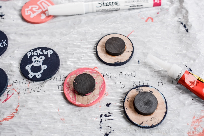 magnets glued to painted wood coins drying on a plastic trash bag