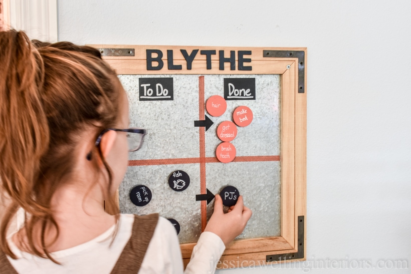 little girl moving using her morning routine chart by moving a magnet from left to right