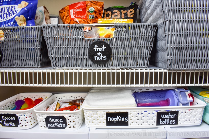 school lunch-packing station inside bottom of pantry closet with baskets for spoons & forks, sauce packets, napkins, and water bottles