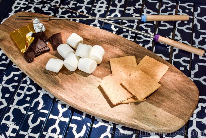 patio table with white patterns from furniture stencil with wood cutting board and s'more supplies