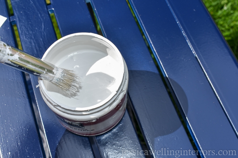 stencil brush dipping into small container of white paint to apply to stencil for painting