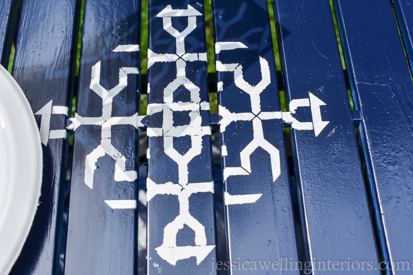 close-up of navy blue patio tabletop with single furniture stencil painted in white