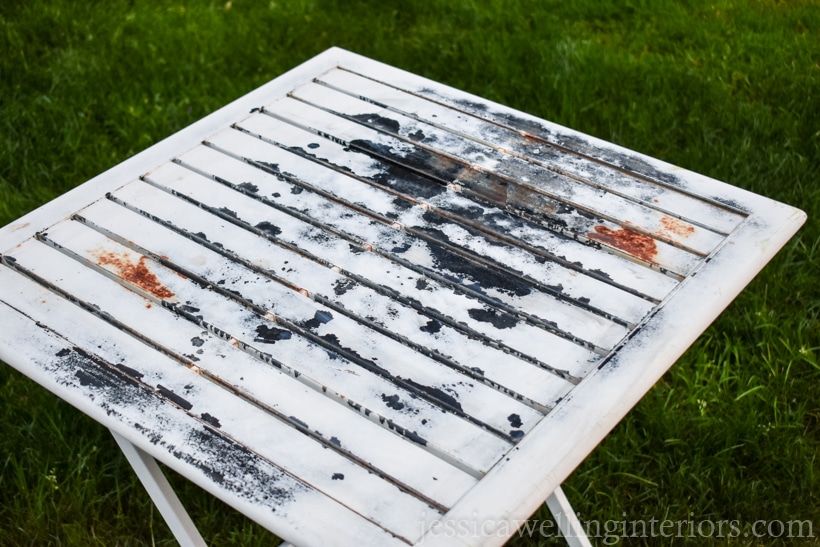 Old metal patio table with peeling paint and rust