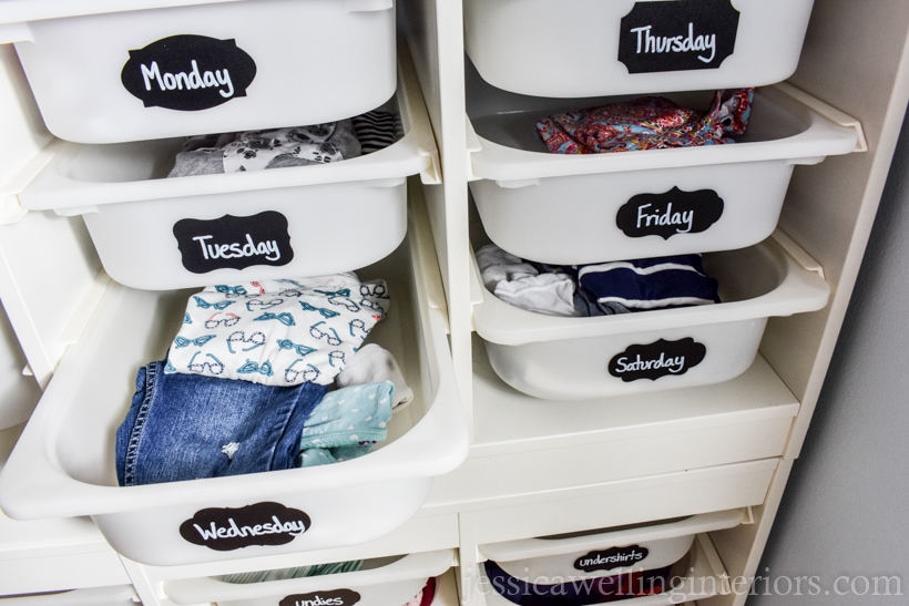 Children's drawer/bins labeled with the days of the week. Each bin has an outfit.
