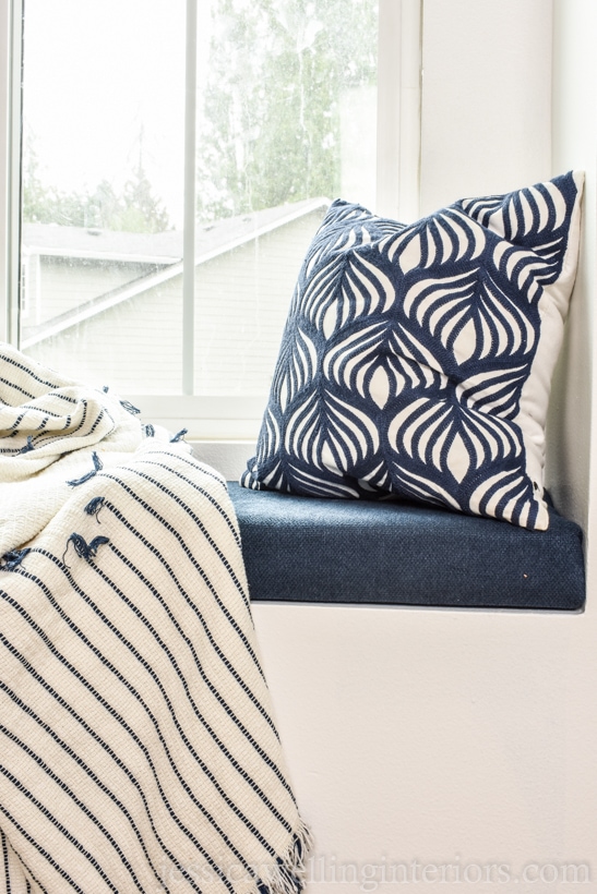 close-up of DIY window seat cushion in kids bedroom with throw pillow and throw blanket