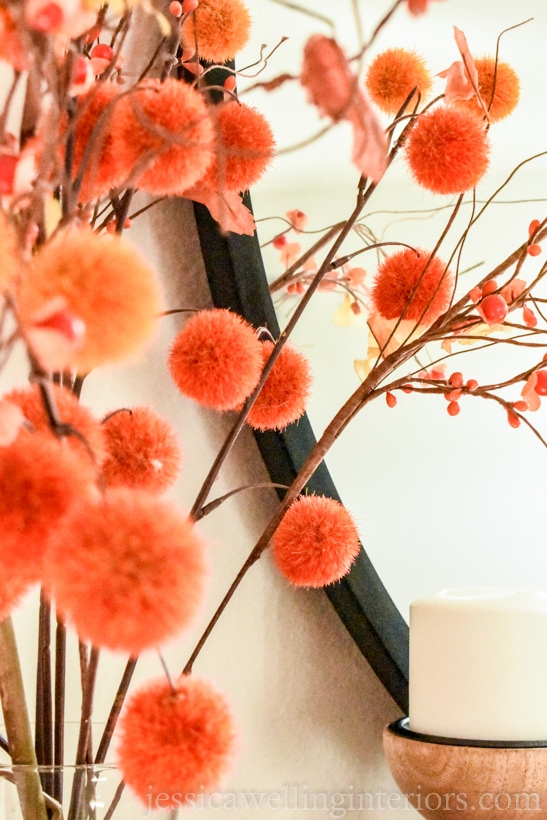 Fall mantel decor close-up of pom-pom stems in front of a round mirror