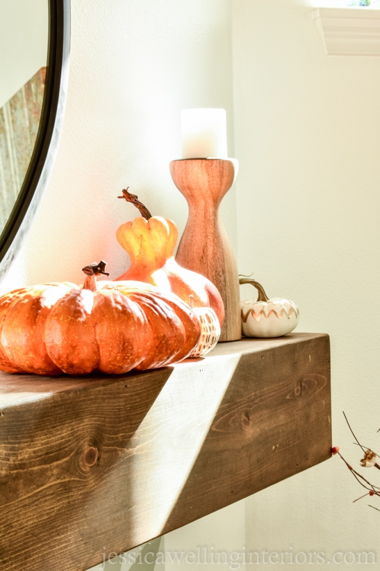 close-up of orange and yellow pumpkins sitting on a wood mantle decorated for Fall