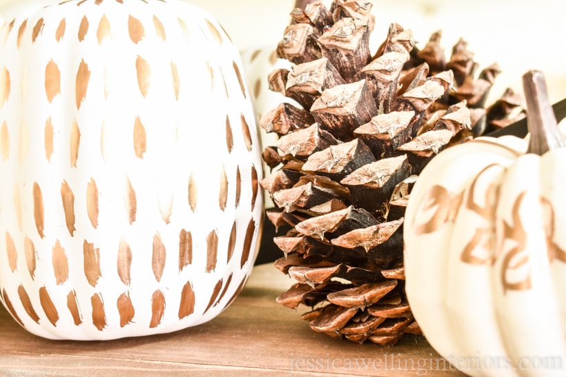 close-up of white pumpkins painted with gold leaf paint and a pinecone