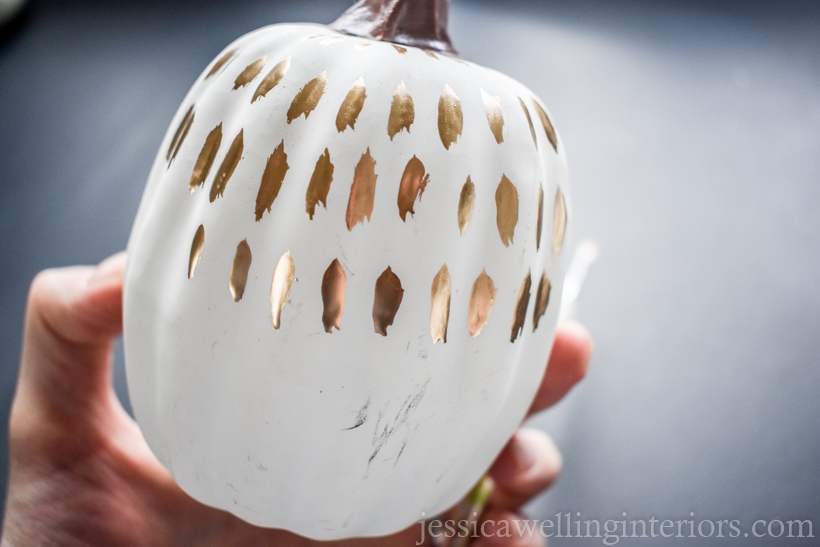 hand holding a white pumpkin with a gold paint pattern for Fall decor ideas