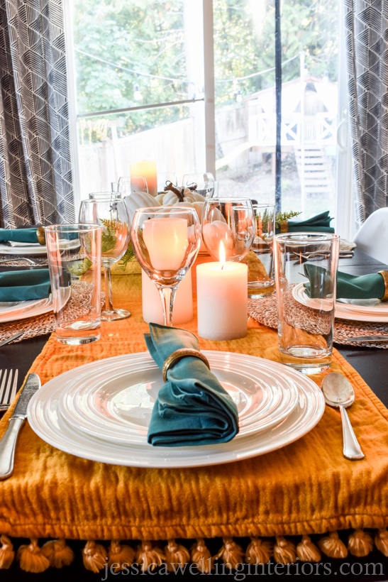 thanksgiving table setting with mustard colored table runner, candles and glasses