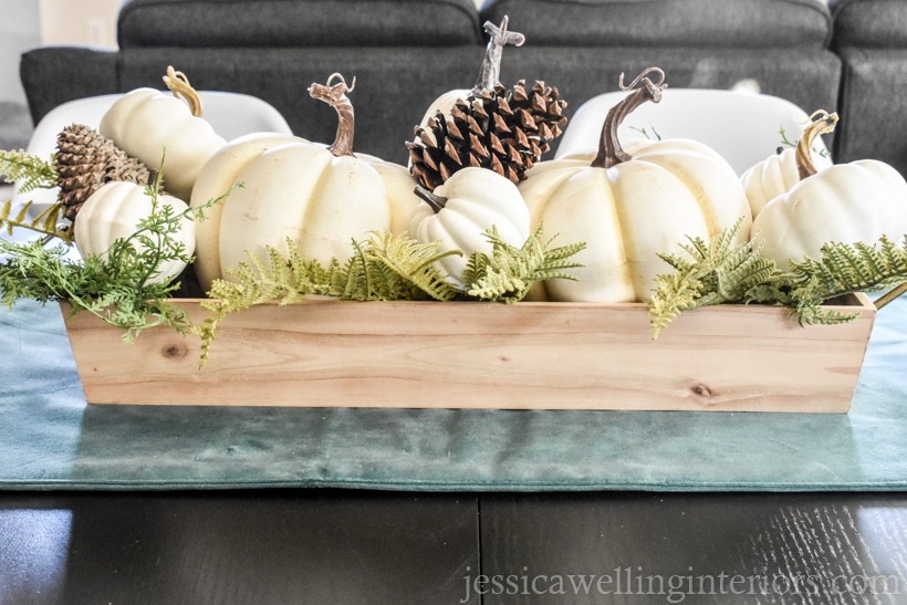 simple white pumpkin centerpiece with pumpkins in a wood tray with foliage and pinecones