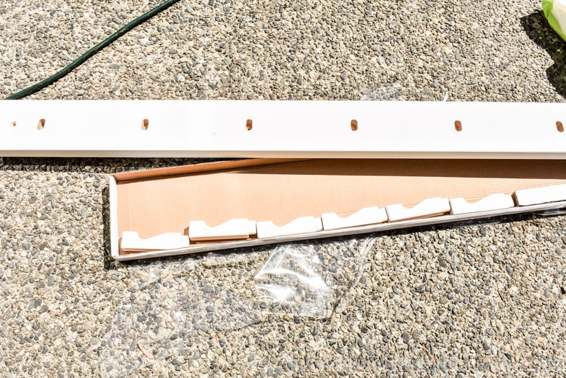 IKEA KUBBIS coat hooks rack partially removed from its package, laying on a cement patio