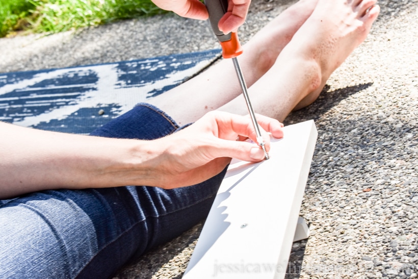 woman using screwdriver to assemble IKEA KUBBIS coat hooks rack on patio