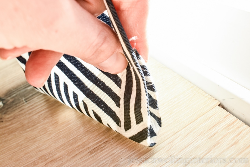 close-up of hand folding hem of curtain panel up to pin it