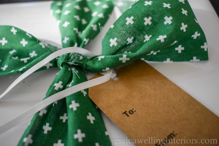 brown paper gift tag being tied onto wrapped gift